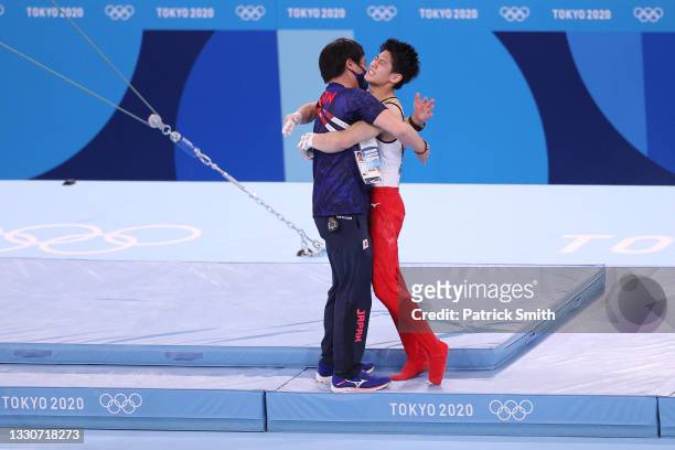 Daiki Hashimoto of Team Japan hugs a coach after competing on horizontal bar during the Men's Team Final on day three of the Tokyo 2020 Olympic Games...