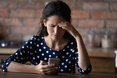 Worried Latin woman having problems with mobile phone