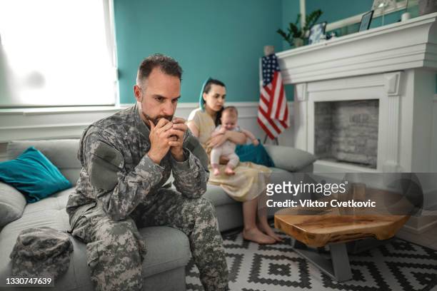 depressed soldier sitting on sofa with his family. - mad husband stock pictures, royalty-free photos & images