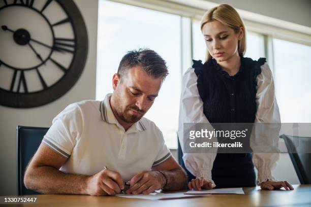 businessman signing legal paper in office - man signing paper stock pictures, royalty-free photos & images