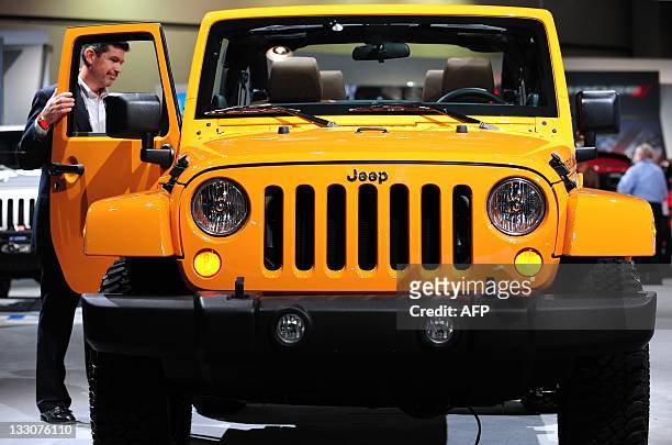 Man opens the passnger door of a Jeep Wrangler on display at the 2012 Los Angeles Auto Show, on November 16, 2011 in Los Angeles, California. Five...