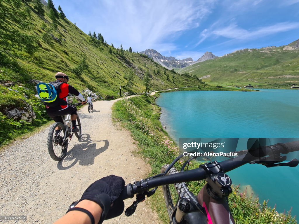 Familia en bicicleta por el lago Tignes en lo alto de los Alpes franceses