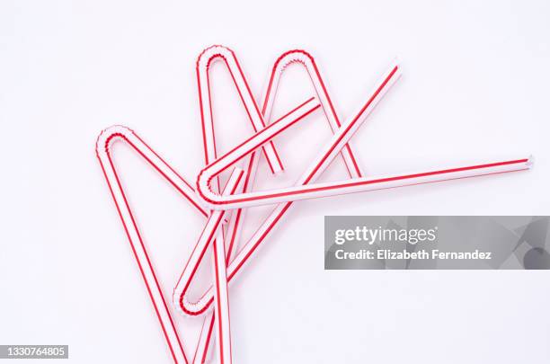 jumble of red and white plastic straws on white background - red straw stock pictures, royalty-free photos & images