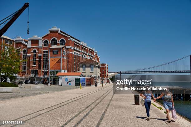 Tourists are seen walking by MAAT museum moments before Portuguese registered "World Navigator" sails the Tagus River after departing Lisbon Cruise...