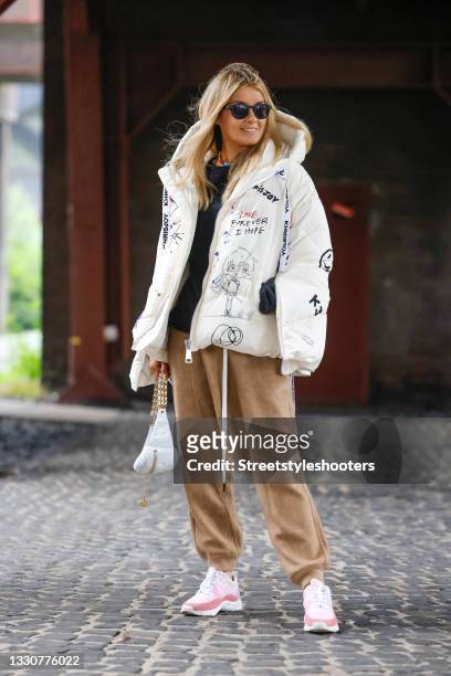 Influencer Gitta Banko wearing a white jacket with multicolored graffiti print by Khrisjoy, slouchy camel colored pants by R13, a dark blue-grey...