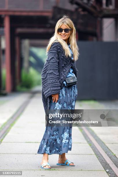 Influencer Gitta Banko wearing a dark blue knitted jacket by Iris von Arnim, a dark and light blue pleated maxi skirt with floral print by Iris von...