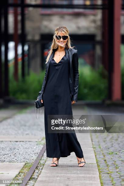 Influencer Gitta Banko wearing a black v-neck maxi dress with leg slit by Victoria Beckham, black sandals by Aquazzura, a black leather jacket by...