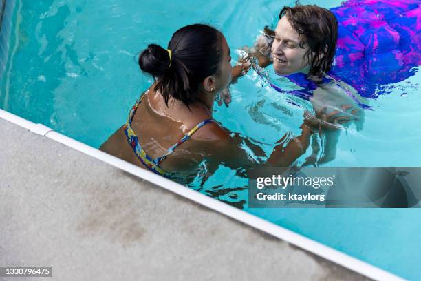 therapeut hilft jungen erwachsenen beim schwimmen im pool - developmental disability stock-fotos und bilder