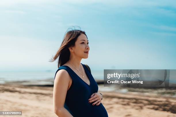 pregnant woman having a walk by the beach - asian woman pregnant stockfoto's en -beelden