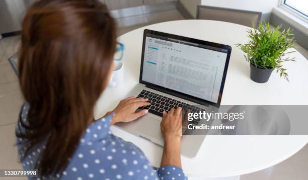 woman telecommuting and reading her e-mail on a laptop at home - assessment 個照片及圖片檔