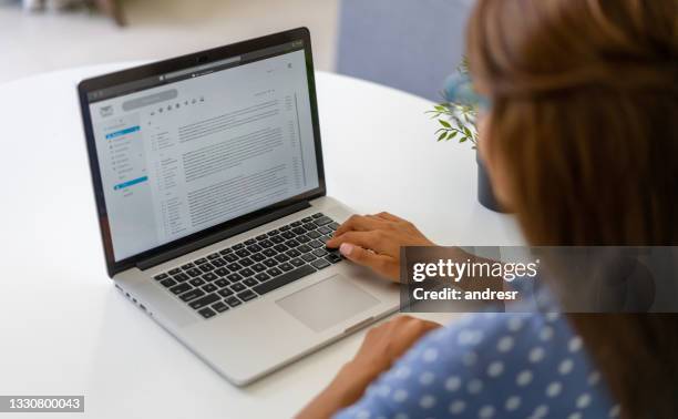woman working at home and reading e-mails on her laptop - e mail inbox stock pictures, royalty-free photos & images