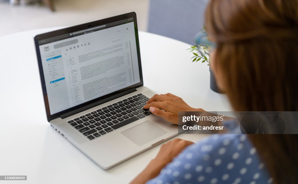 Mulher trabalhando em casa e lendo e-mails em seu laptop