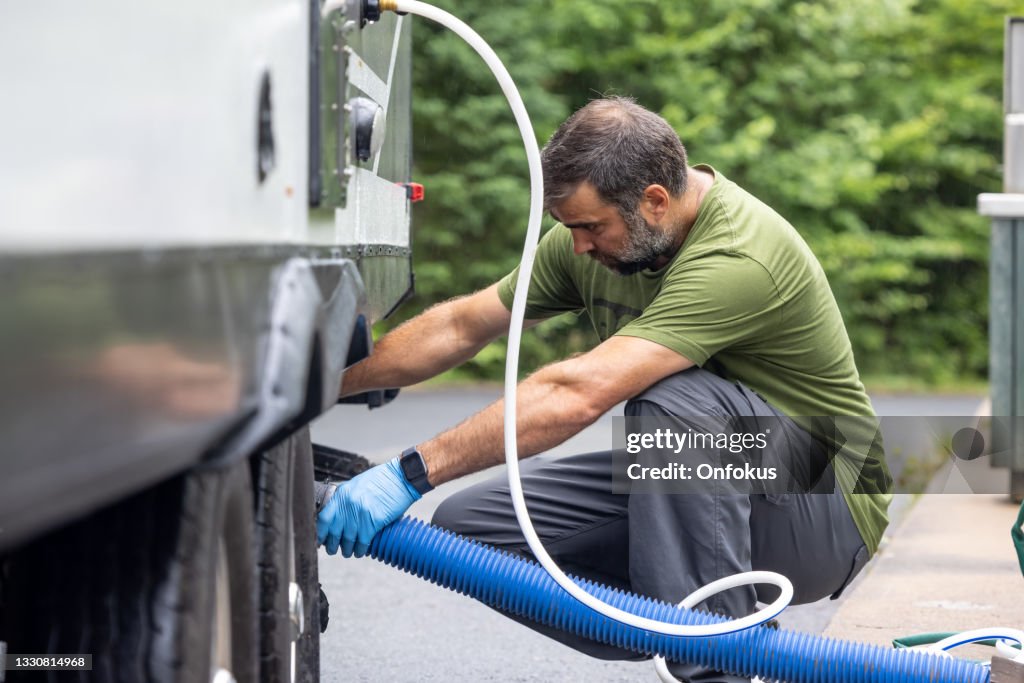 Man Emptying RV Sewer at Dump Station After Camping