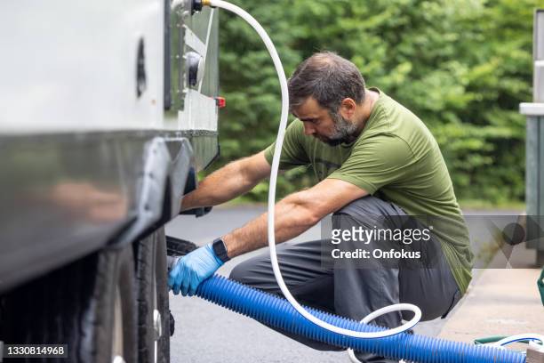 man emptying rv sewer at dump station after camping - sewage services stock pictures, royalty-free photos & images