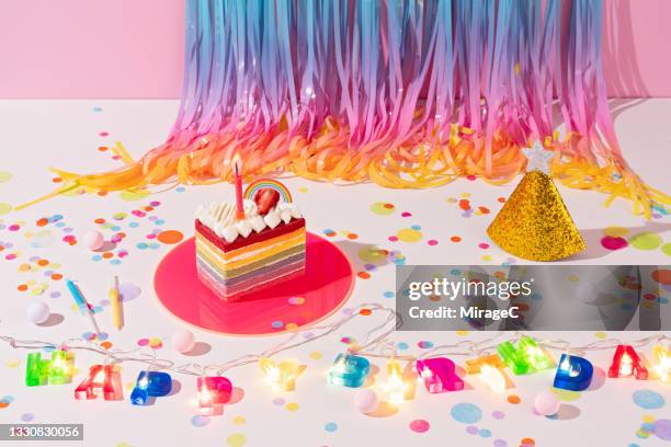 birthday party decorations ideas of rainbow cake and tinsel - birthday streamers stock-fotos und bilder