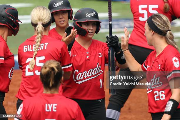 Kelsey Harshman of Team Canada gets high-fives from Jennifer Gilbert and Larissa Franklin after hitting a sacrifice fly that drove in Janet Leung to...