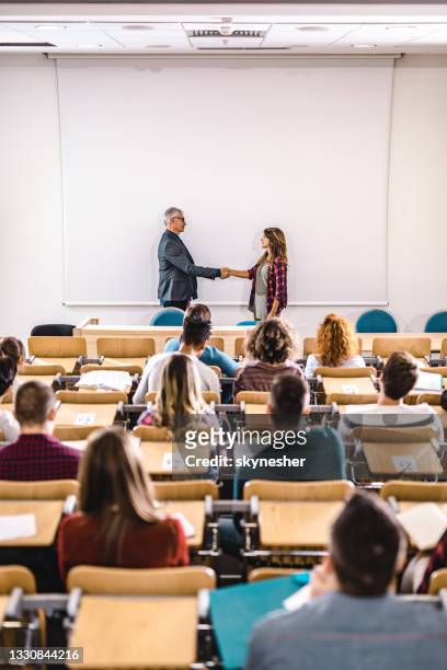 glücklicher professor und college-student, der sich vor dem whiteboard die hände schüttelt. - schulabschluss stock-fotos und bilder