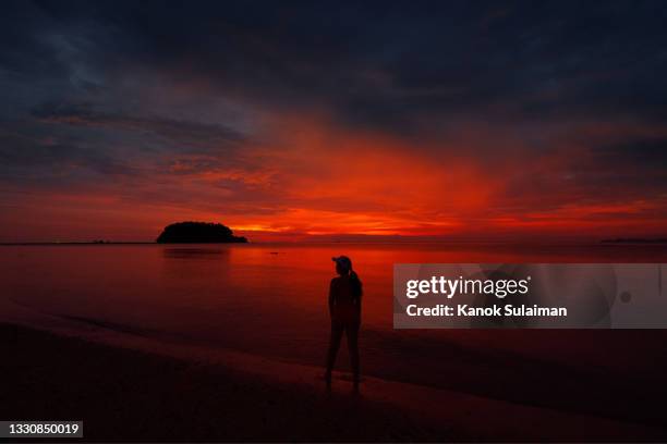 woman standing in sea against sky - red sky stock-fotos und bilder