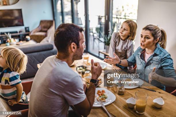 young parents arguing while having lunch with their kids at home. - family arguing stock pictures, royalty-free photos & images