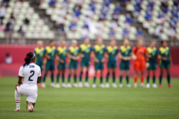 Crystal Dunn of Team United States takes a knee in support of the Black Lives Matter movement as Team Australia stand prior to the Women's Football...