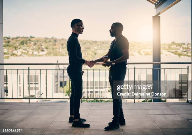 shot of two businessmen shaking hands on the balcony of an office - handshake silhouette stock pictures, royalty-free photos & images