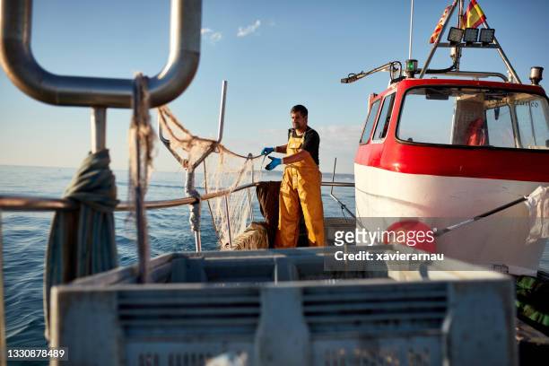 independent commercial fisherman managing nets onboard boat - trawler stockfoto's en -beelden