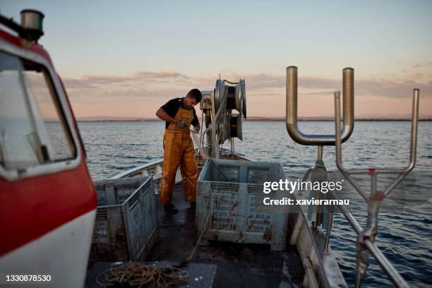 pêcheur adulte moyen retirant les prises du filet - pêcheur photos et images de collection