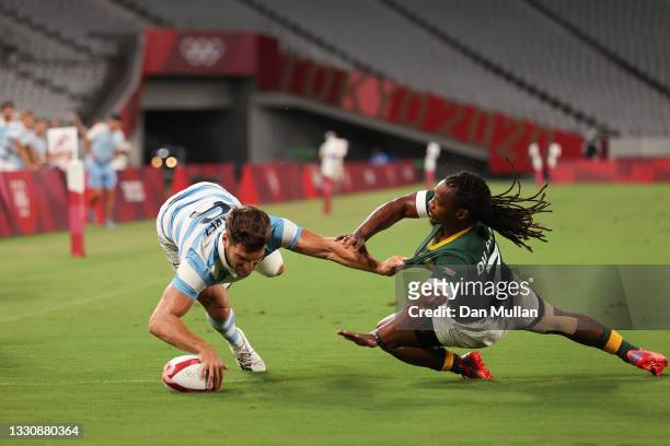 Santiago Alvarez of Team Argentina scores a try while getting tackled by Branco du Preez of Team South Africa during the Rugby Sevens Men's...