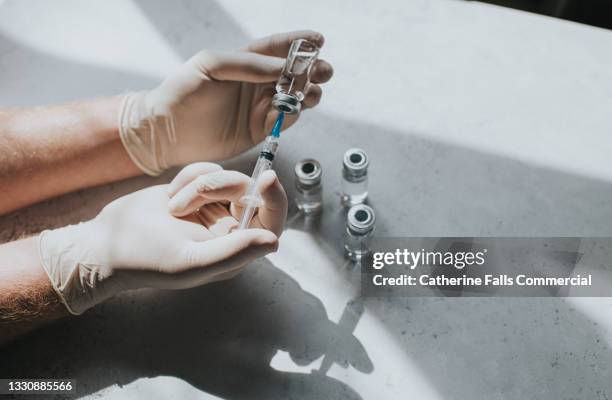 gloved hand holds a syringe and a phial - conceptual medical image with space for copy. - vaccination imagens e fotografias de stock