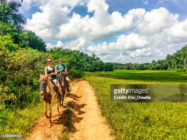 turistas a caballo y cubanos con el carro en el valle de viñales (cuba) - viñales cuba fotografías e imágenes de stock