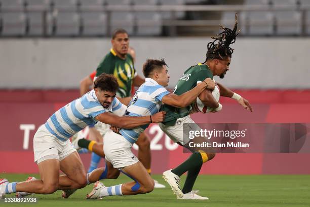 Selvyn Davids of Team South Africa is tackled by Marcos Moneta of Team Argentina on his way to scoring a try during the Rugby Sevens Men's...