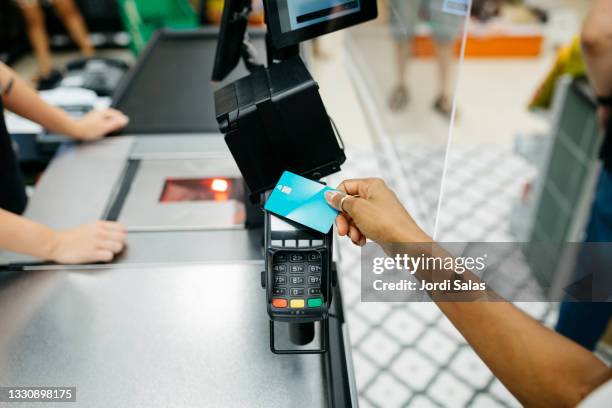close up of a hand paying with a credit card in a supermarket - leitor de cartão de crédito imagens e fotografias de stock