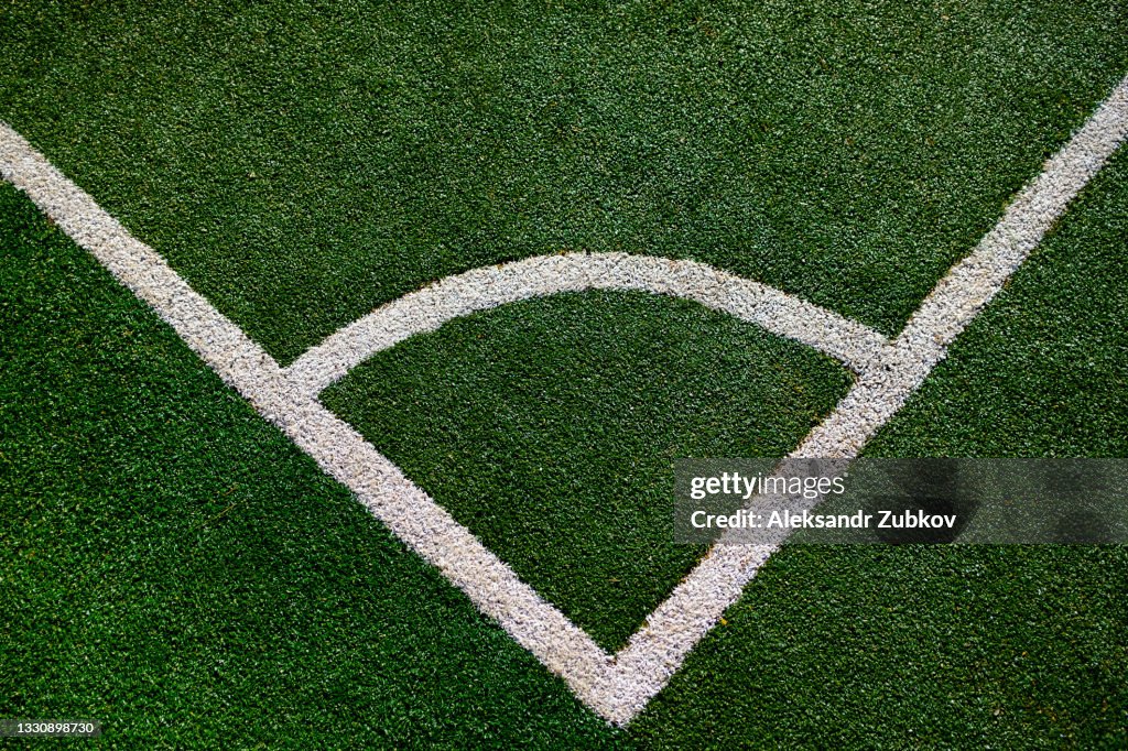Part of the layout of the football field, the position of the corner kick. White marking lines on the green grass of the sports stadium.