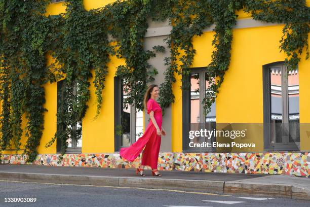 young beautiful woman in long pink dress walking on the street - long bright yellow dress stock pictures, royalty-free photos & images