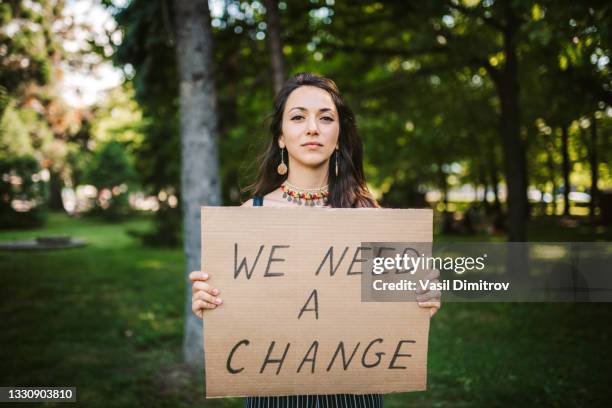 young activist / protester with a "we need change"  poster - activists protests outside of trump tower in chicago stockfoto's en -beelden