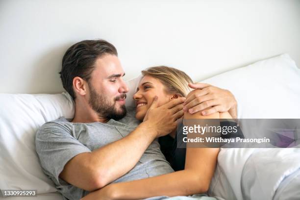 joyful loving couple luxuriating in bedroom together - good night kiss - fotografias e filmes do acervo