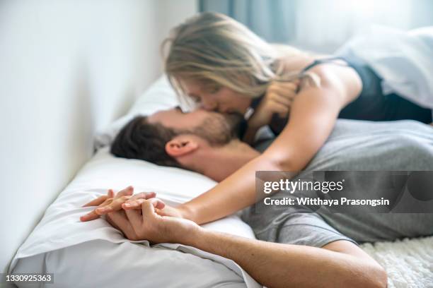 the young couple kissing in the bed - paar partnerschaft stock-fotos und bilder