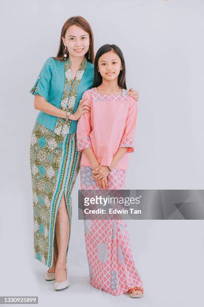 studioporträt malaysisch chinesisch schöne mutter und tochter mit batikkleid malaiische tradition kleidung mit weißem hintergrund blick auf die kamera lächelnd - malay culture stock-fotos und bilder