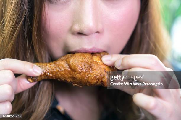 woman portrait holding chicken meat and biting - woman eating chicken photos et images de collection