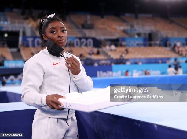 Simone Biles of Team United States supports her team mates by carrying their chalk after pulling out after the vault during the Women's Team Final on...