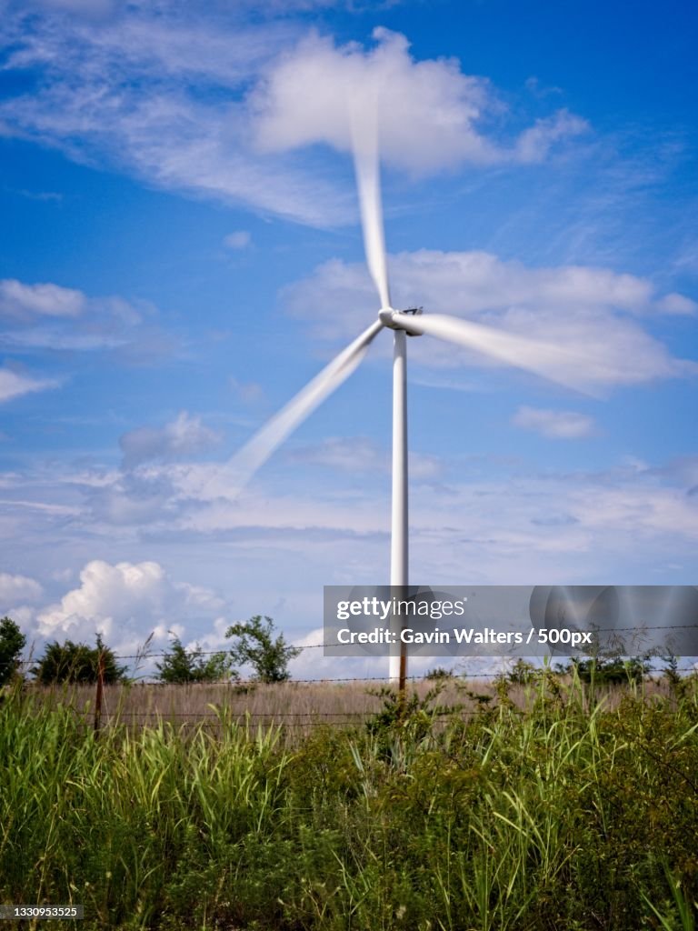 Low angle view of windmills on field against sky