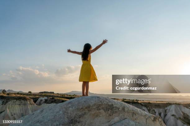 cute little girl in a yellow dress watching the valley of cappadocia, turkey - göreme stock pictures, royalty-free photos & images