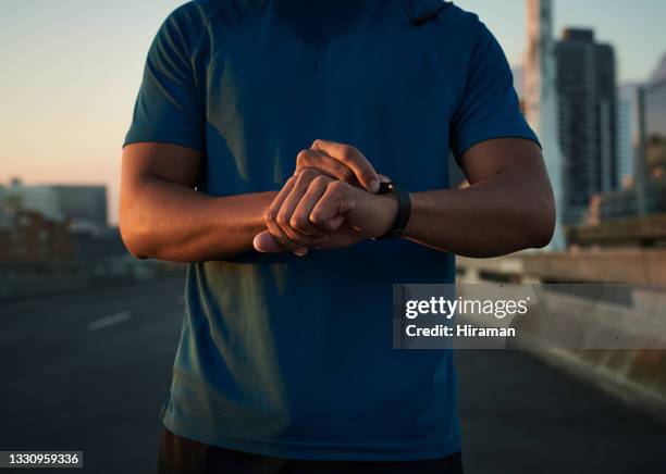 cropped shot of a handsome young man standing alone in the city and checking his watch before his morning run - running man heartbeat stock pictures, royalty-free photos & images