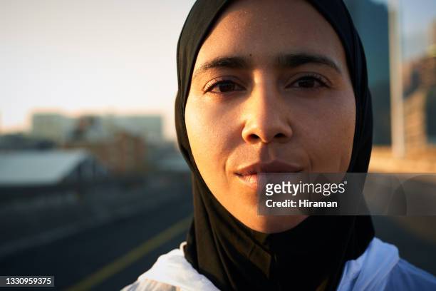 shot of an attractive muslim woman standing alone in the city before her morning run - determination face stock pictures, royalty-free photos & images