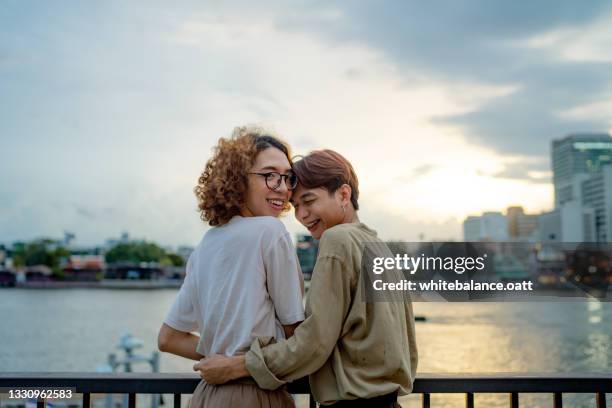 lgbtqia couple resting at waterfront. - nb stock pictures, royalty-free photos & images