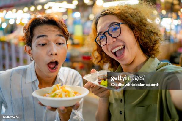 Two vlogger filming a video with their street food.