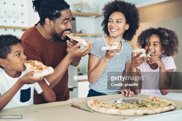 family with two children having pizza at home - family eat imagens e fotografias de stock
