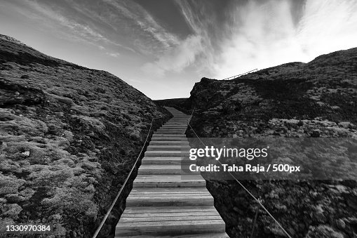 Empty footpath leading towards mountains against sky Empty footpath leading towards mountains against sky
