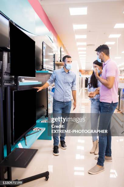 looking for a tv while wearing masks during covid-19 pandemic - retailer shopping customer tv stockfoto's en -beelden