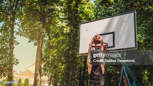 the young man warms up for basketball on the court in his neighborhood - basket universitario imagens e fotografias de stock